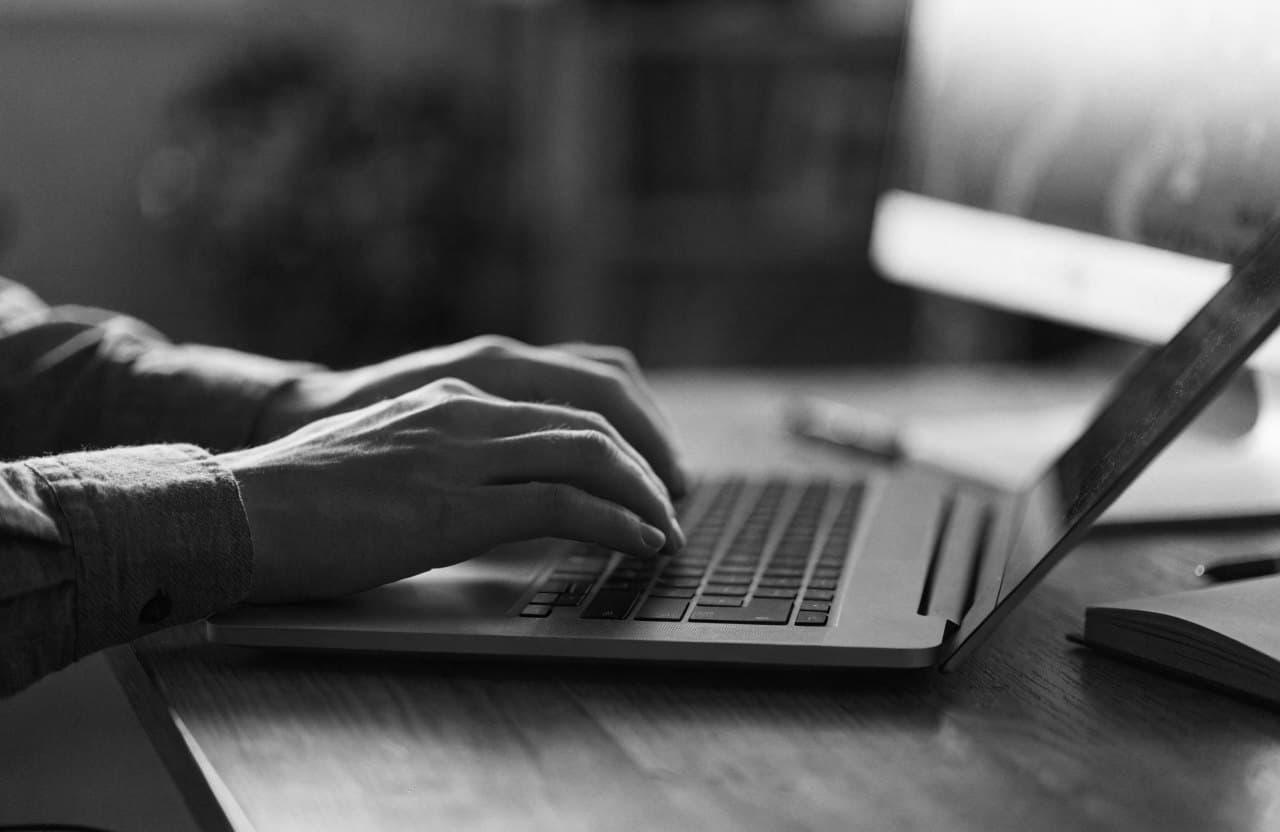 Les mains d'un participant sur le clavier d'un ordinateur portable, un second écran en arrière-plan